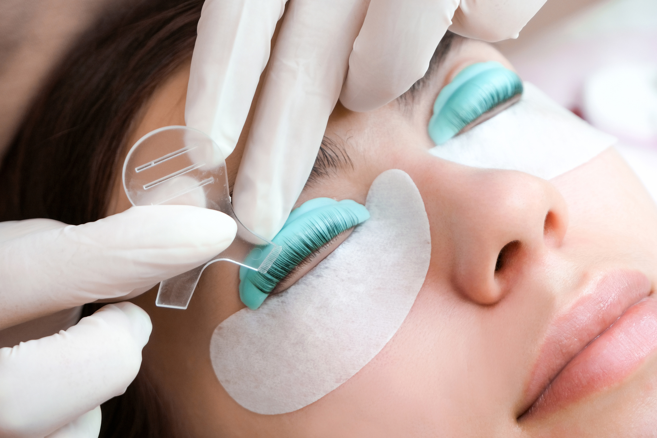 Young woman doing eyelash lamination procedure in a beauty salon, close-up