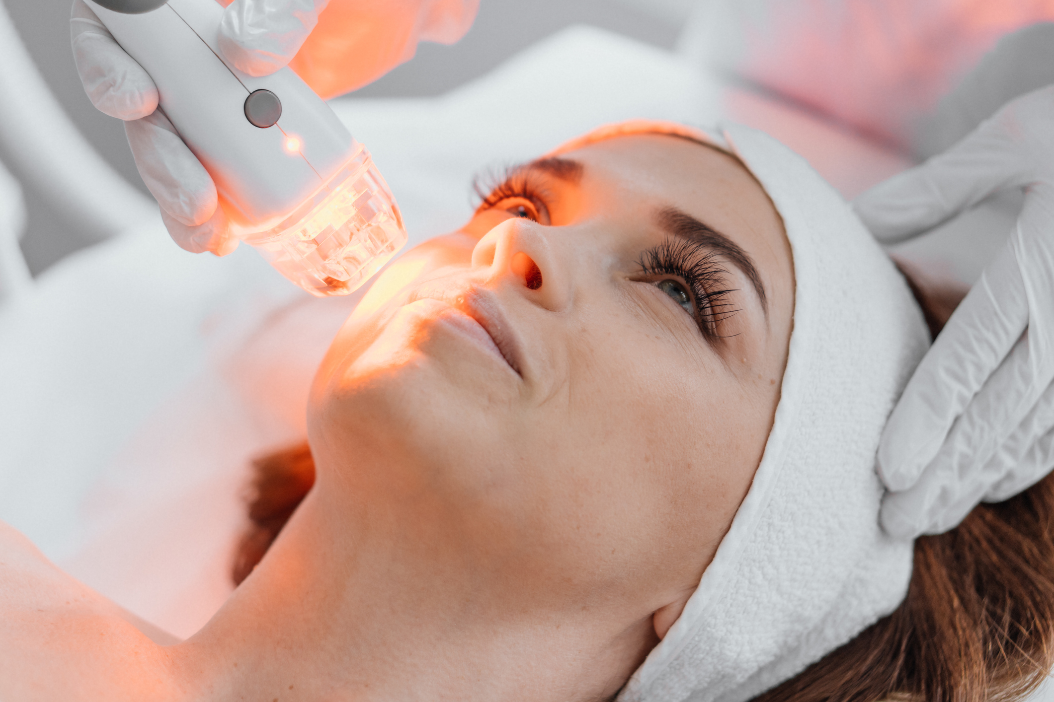 Photo from the studio of cosmetology, demonstrating the process of led therapy and facial skin care. A woman undergoes a procedure in a beauty salon. Beautician in white gloves use. High quality photo